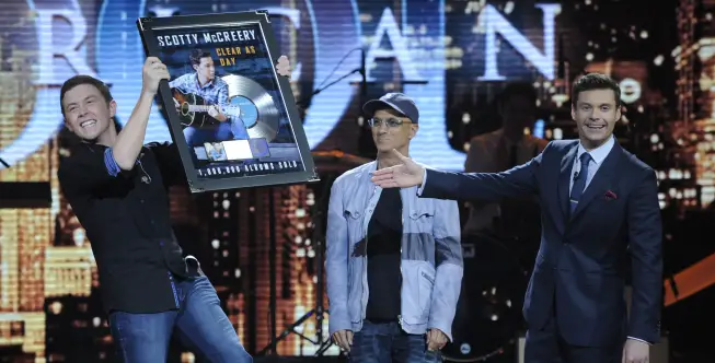 AMERICAN IDOL: Scotty McCreary is presented with a platinum record for CLEAR AS DAY on AMERICAN IDOL airing Thursday, March 29 (8:00-9:00PM ET/PT) on FOX. Pictured L-R: Scoty McCreary, Jimmy Iovine and Ryan Seacrest. CR: Phil Mcarten / FOX.